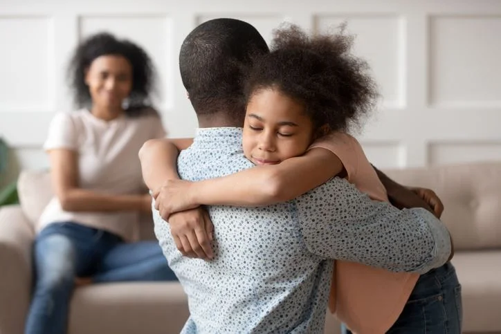 Man hugging his daughter with his wife smiling in the background