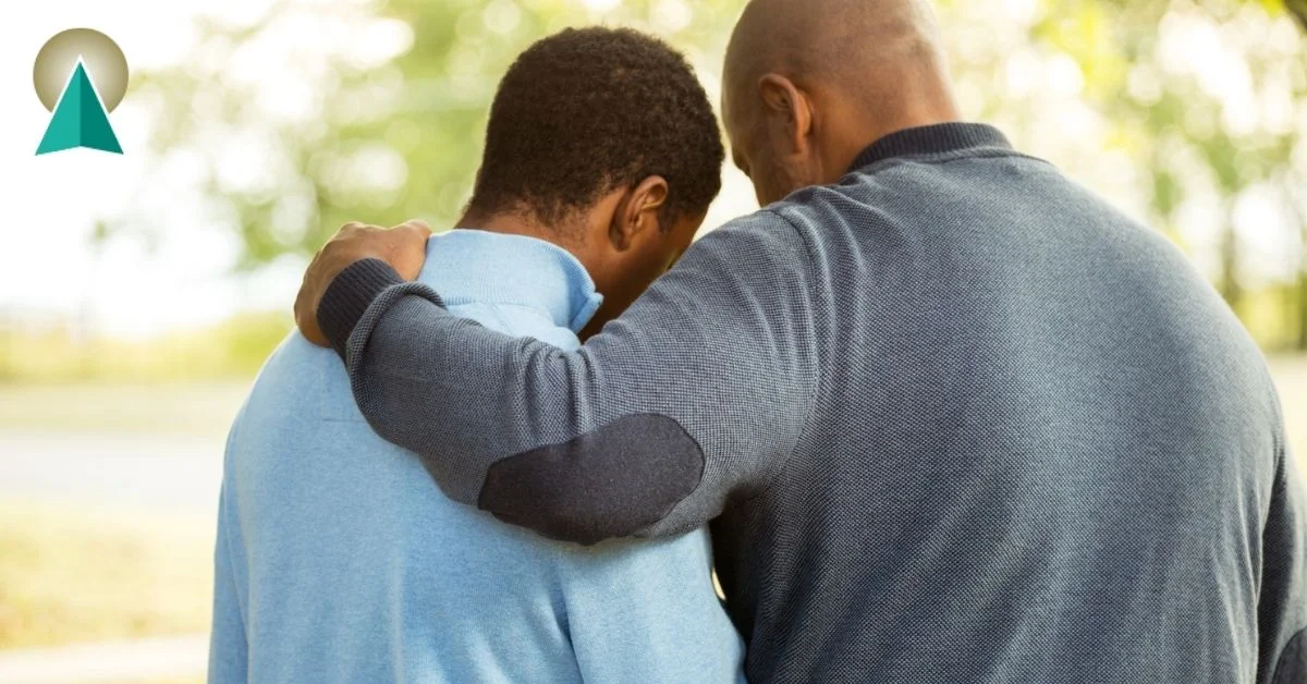 Dad with his arm wrapped around his young adult aged son.