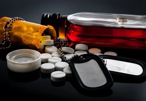 Whiskey bottle and spilled bottle of prescription drugs with a military dog tag
