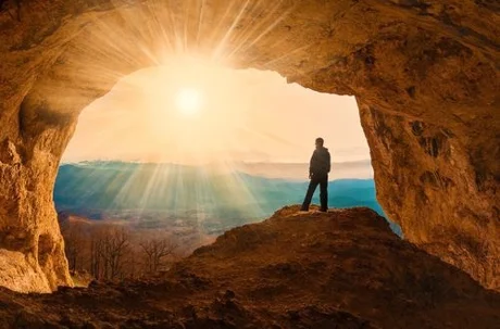 man in cave looking at sunset