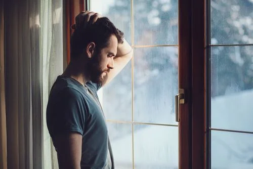Man looking somber near window