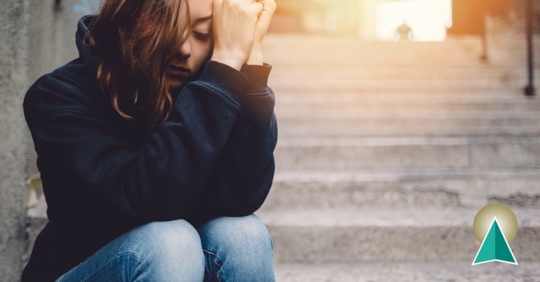 Girl sitting on steps with her head in her hands