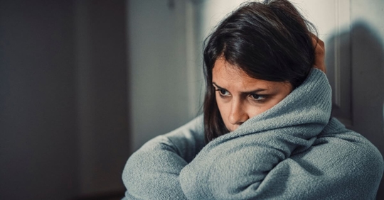 Young girl with her arms around her head looking sad.