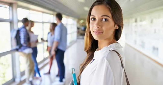Student standing in a school hallway, looking back at the camera