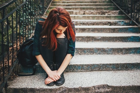 Depressed teenage girl sitting on outdoor staircase