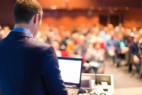 man standing at podium giving speech looking at crowd