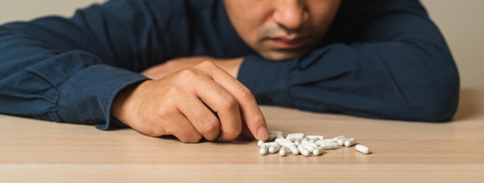 stressed man looking at pills