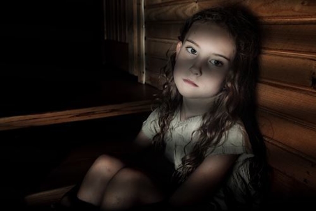 sad little girl sitting alone in the dark