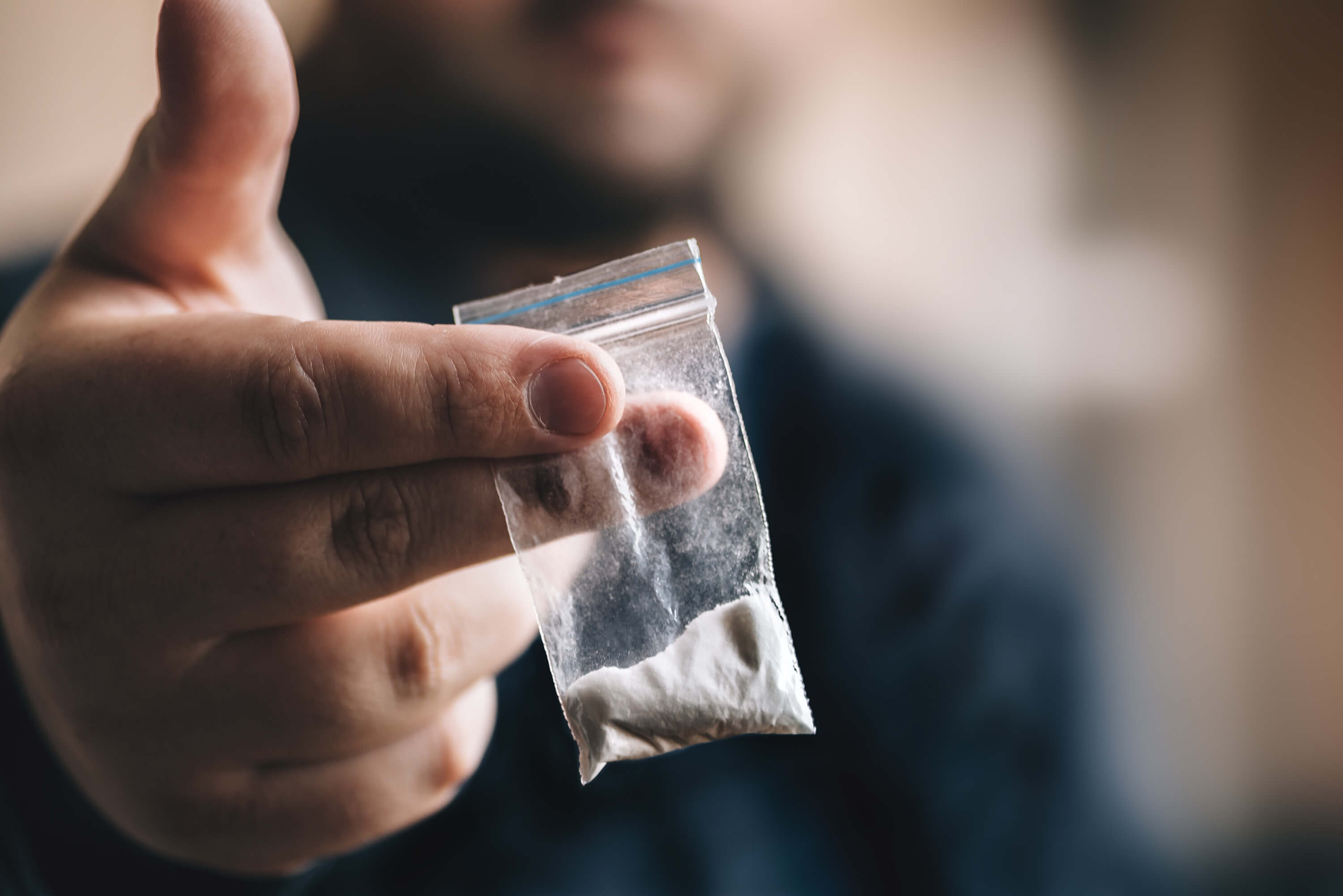closeup photo of a hand holding a small bag of cocaine