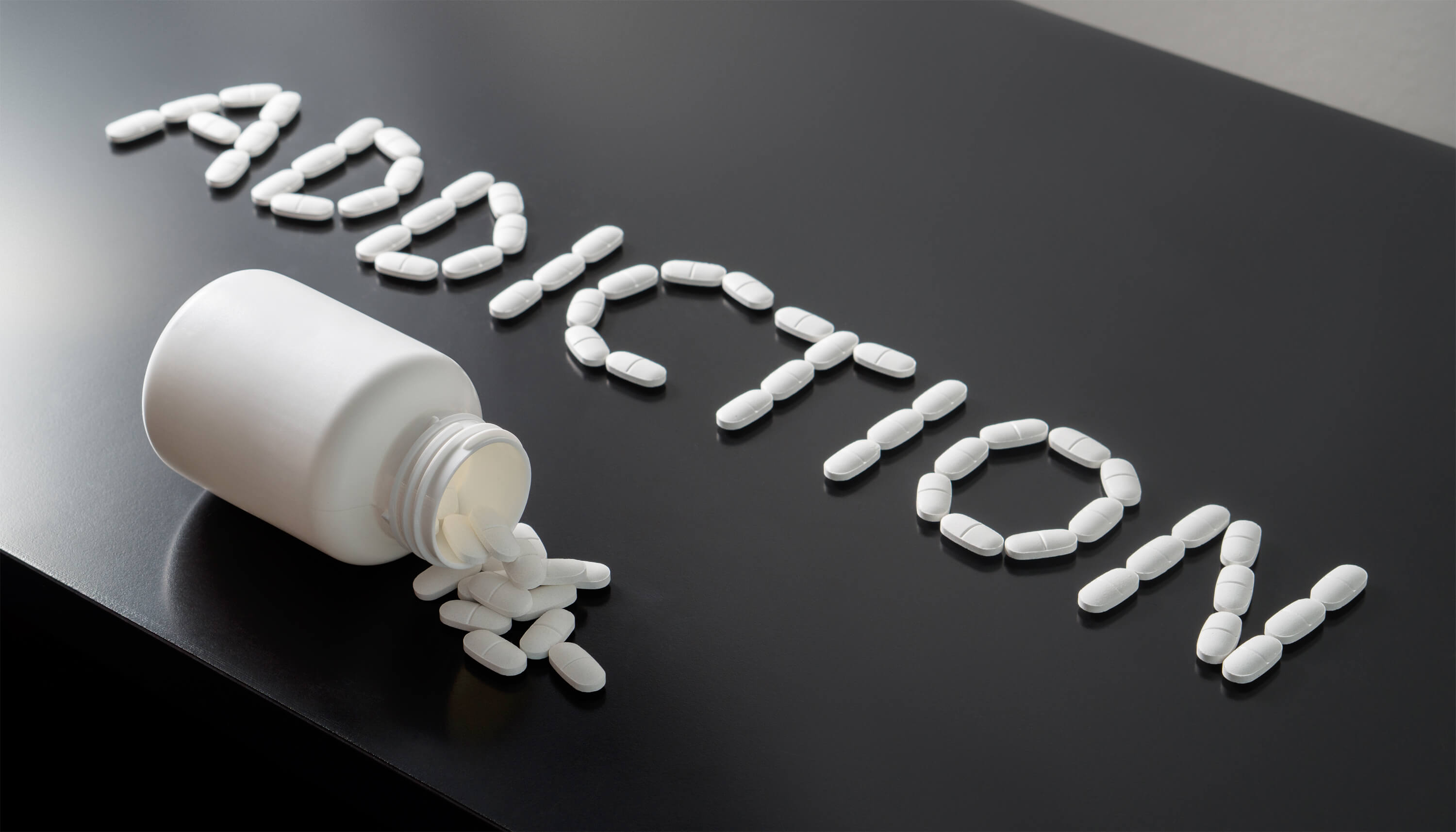 the word "addiction" spelled with prescription pills on black tabletop